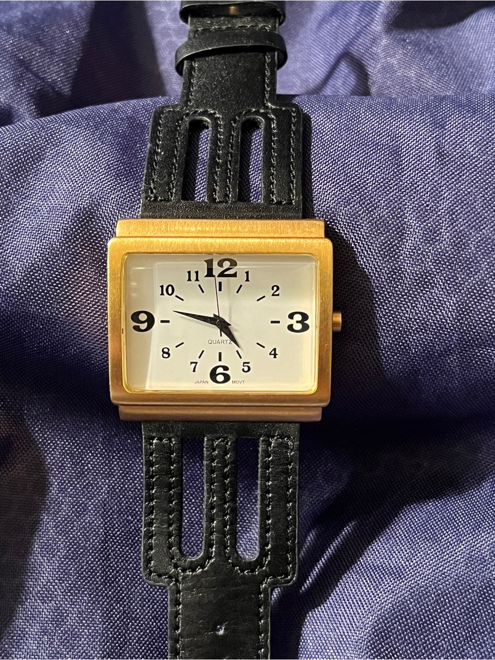 Rectangular gold-tone quartz wristwatch with unique cut-out black
strap